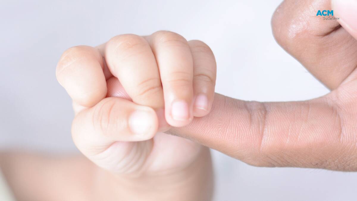 A tiny baby hand grasps its parent's finger. Picture Canva